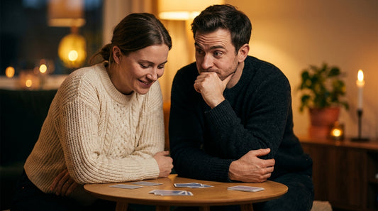 Un couple complice joue à un jeu de cartes Oh Happy Games à la lueur des bougies